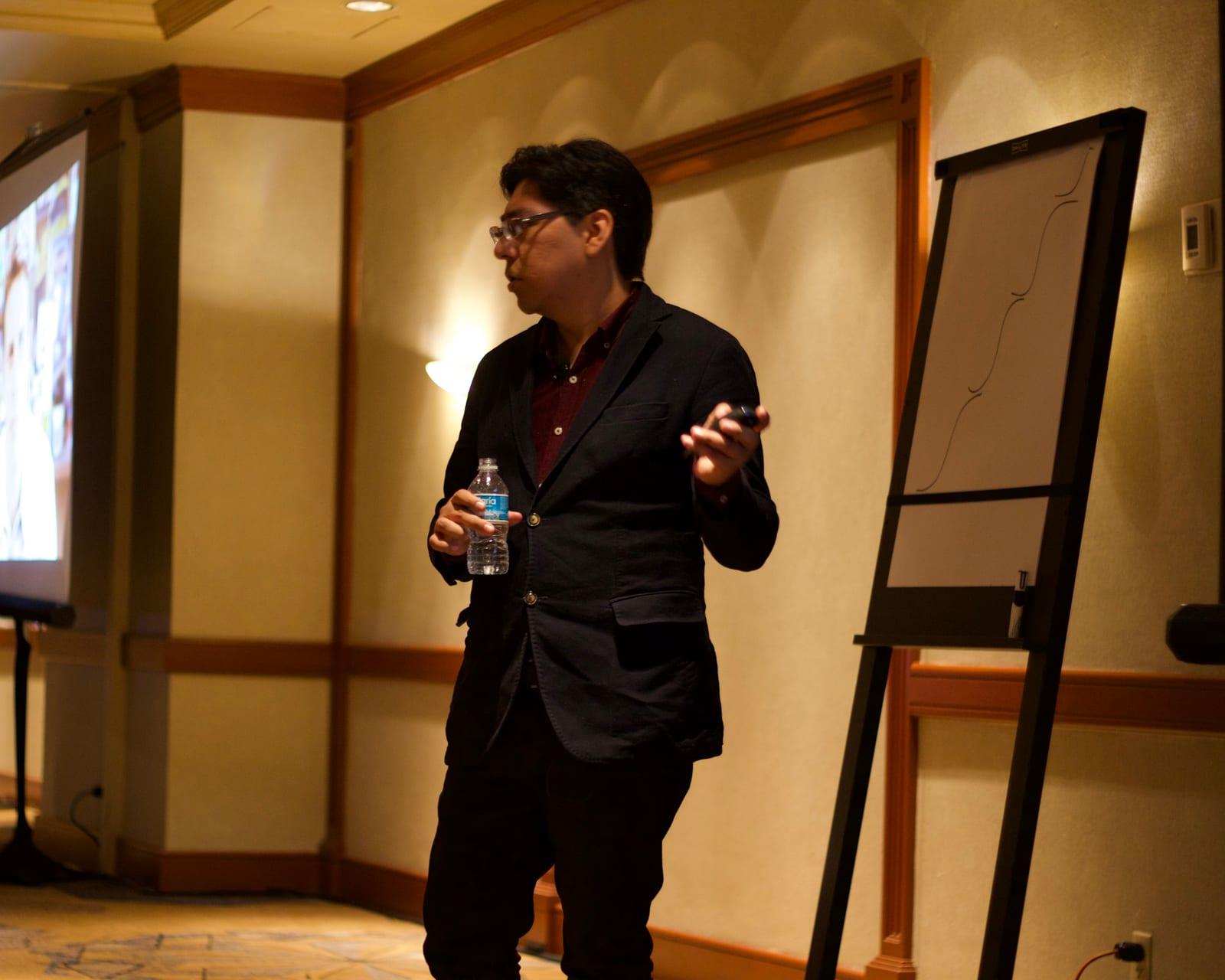 Yamil talking to the room beside a flip chart
