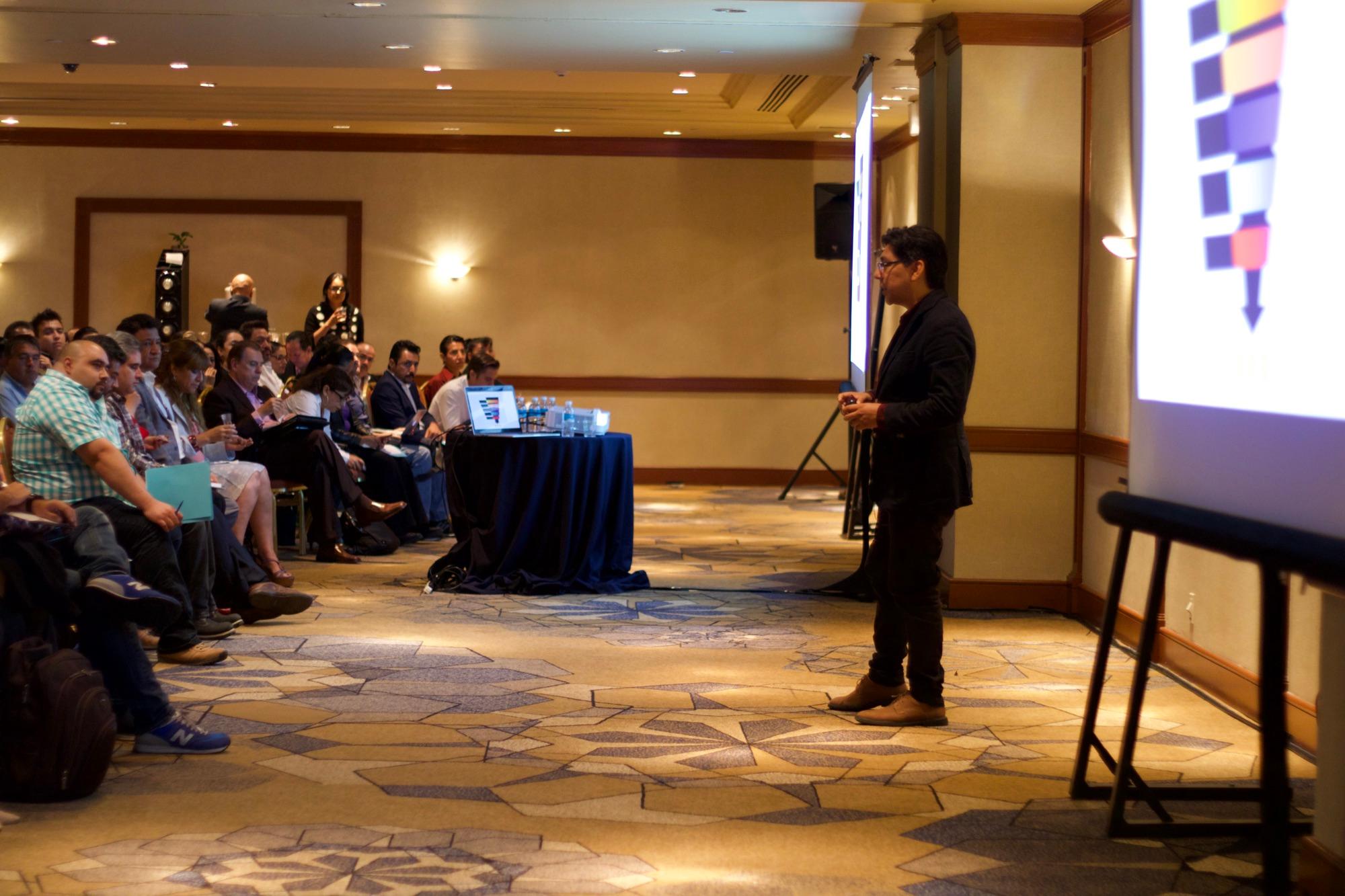 Yamil Morales presenting at the front of a hotel ballroom